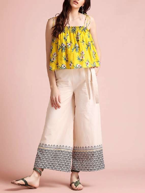 a bright set with printed yellow top and beige flared pants.